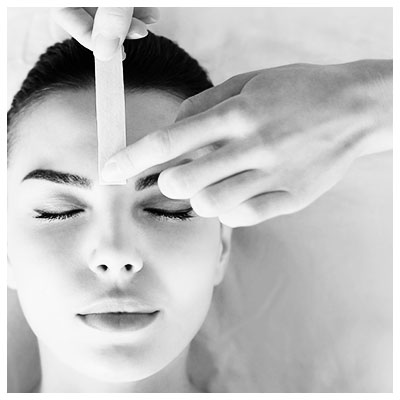 Image of girl getting her eyebrows waxed.